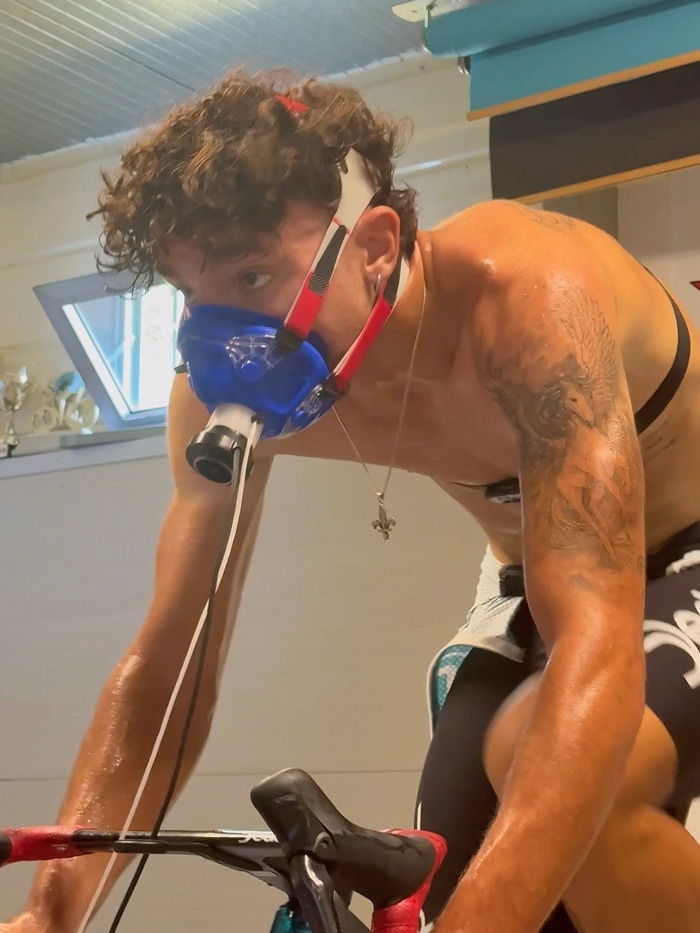 Atleta a fine protocollo incrementale, sudato e piegato sul manubrio