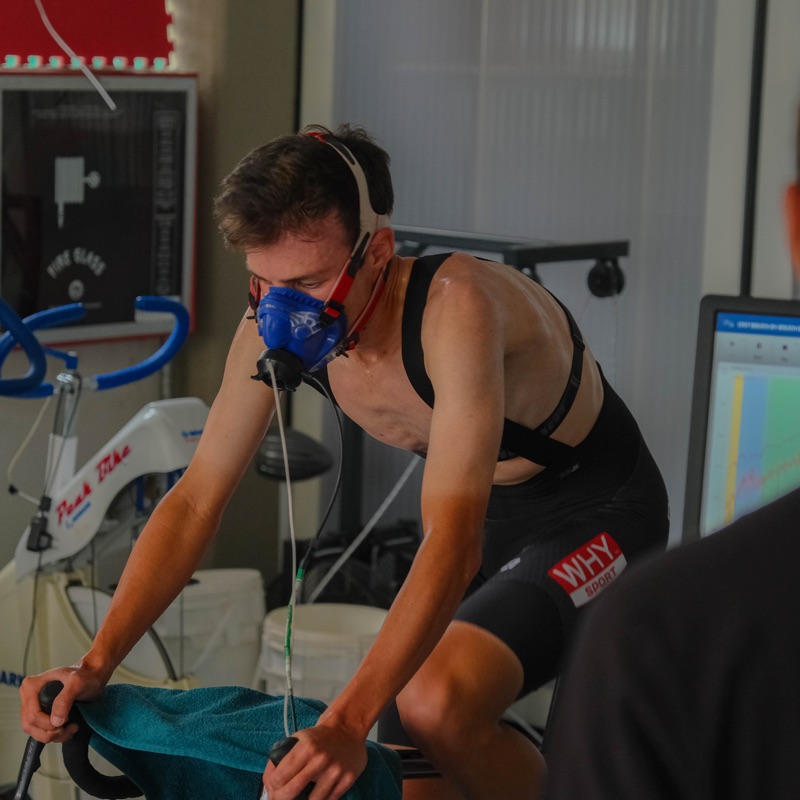 Atleta con la maschera durante il protocollo incrementale, accanto al monitor con le curve del test