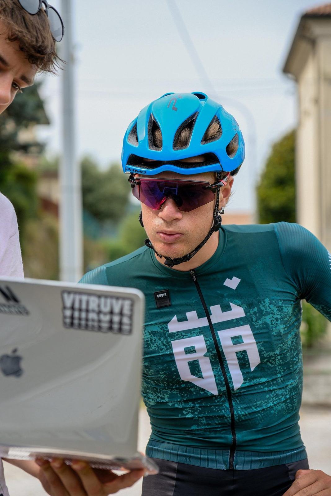 Atleta in casco legge i dati sul laptop dopo un test sul campo