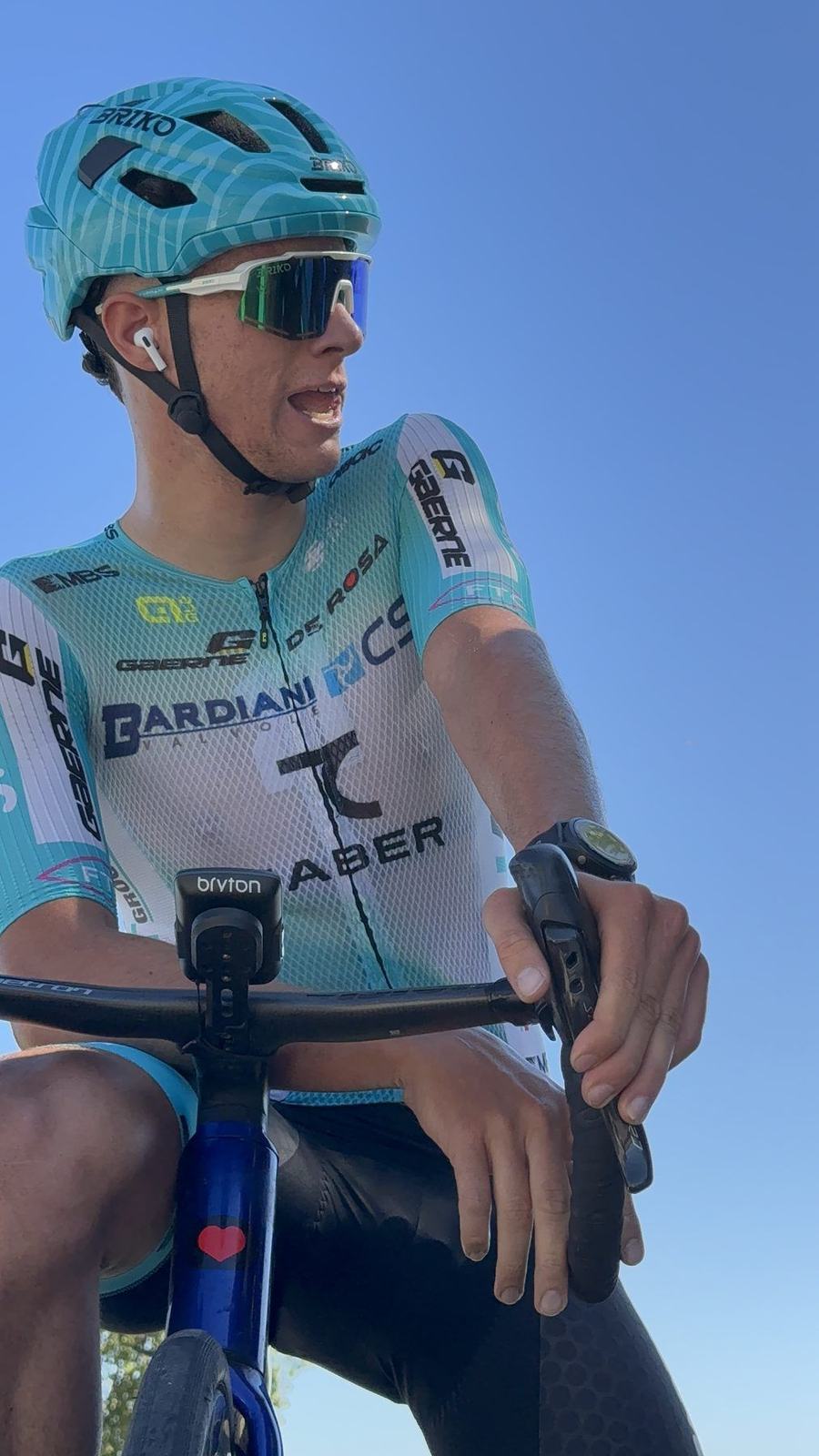 Atleta in maglia azzurra fermo in bici, lo sguardo basso, prima di ripartire