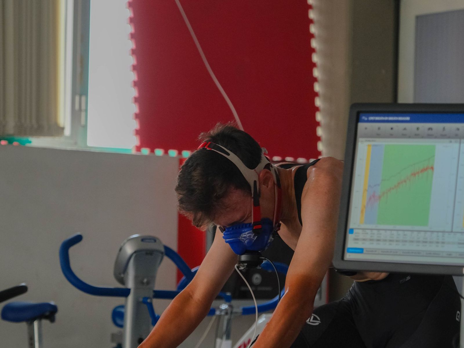 Atleta sotto sforzo con la maschera, accanto al monitor con le curve del test